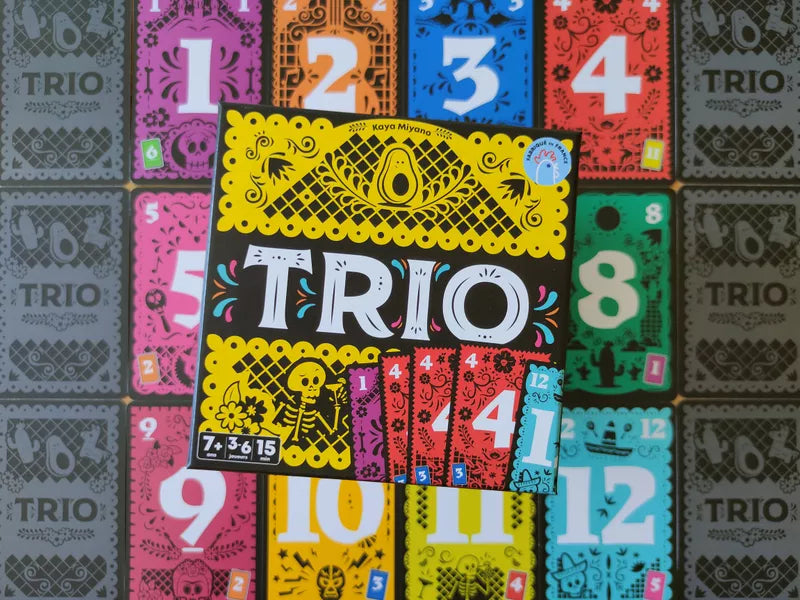 Componenti di Trio: carte numerate e regolamento su tavolo di legno